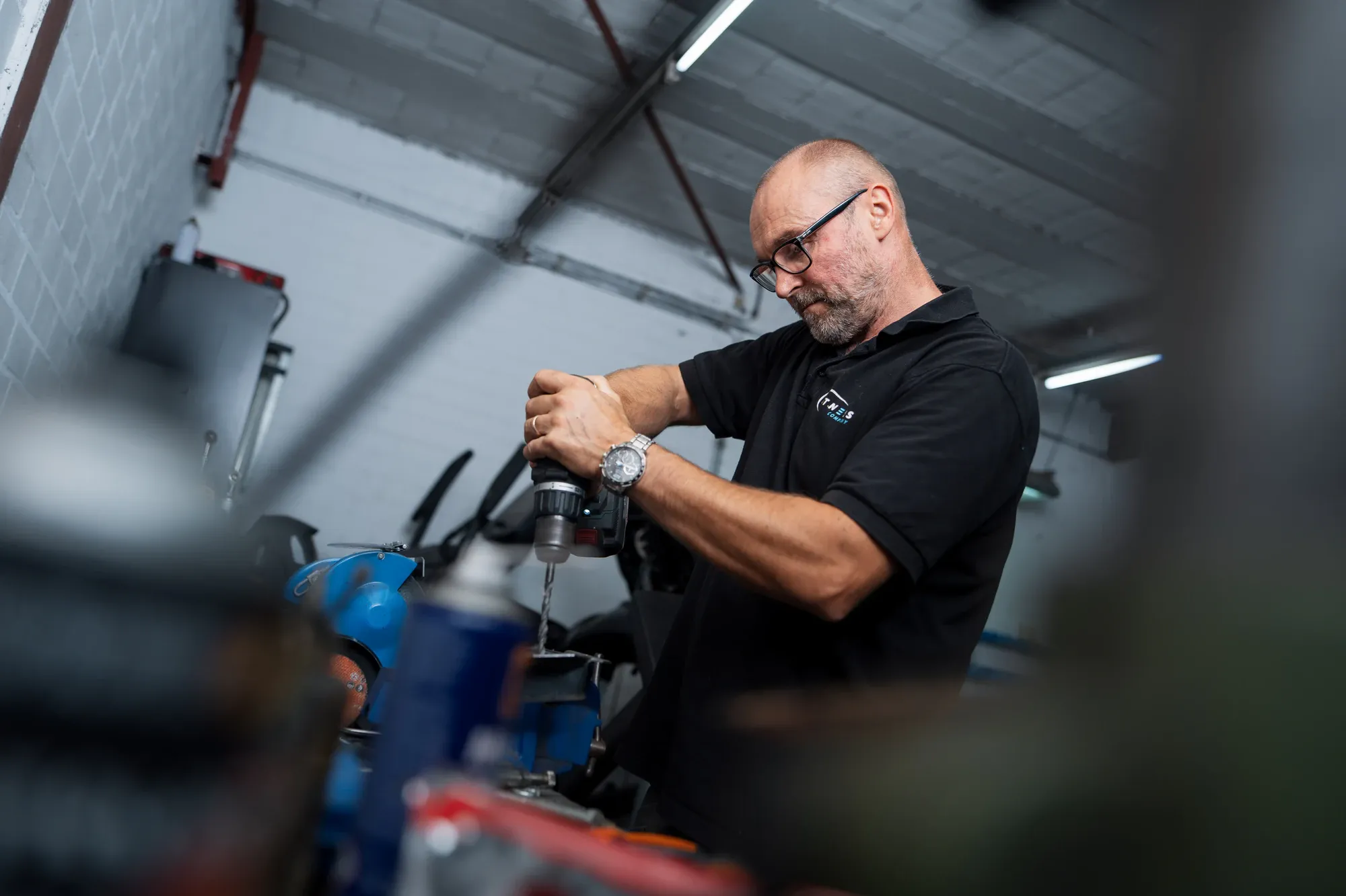 Monteur van Fitness Company boort aan een fitnesstoestel in de eigen werkplaats
