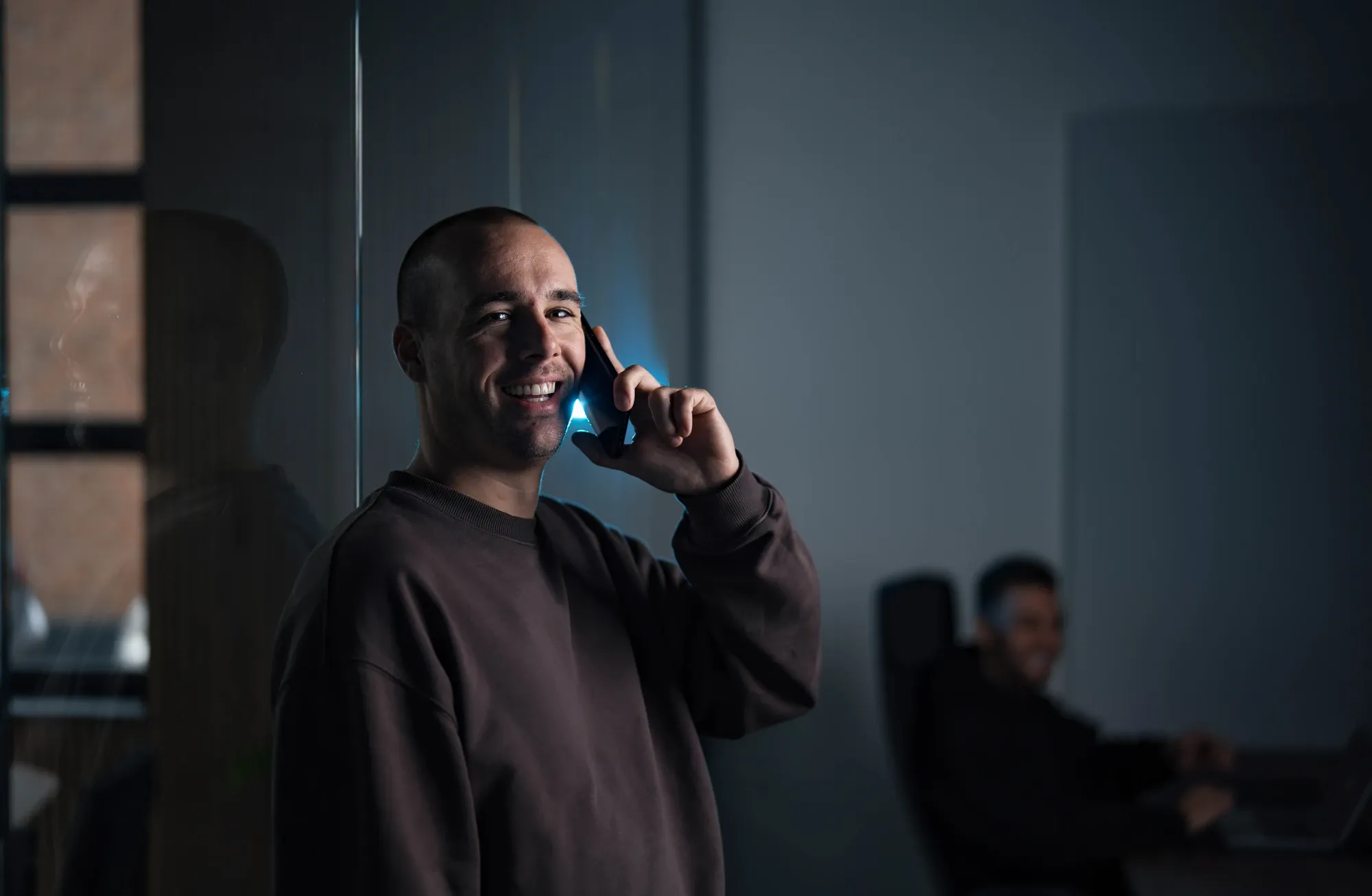 Collega van Klubb belt met een mobiele telefoon bij het raam op kantoor