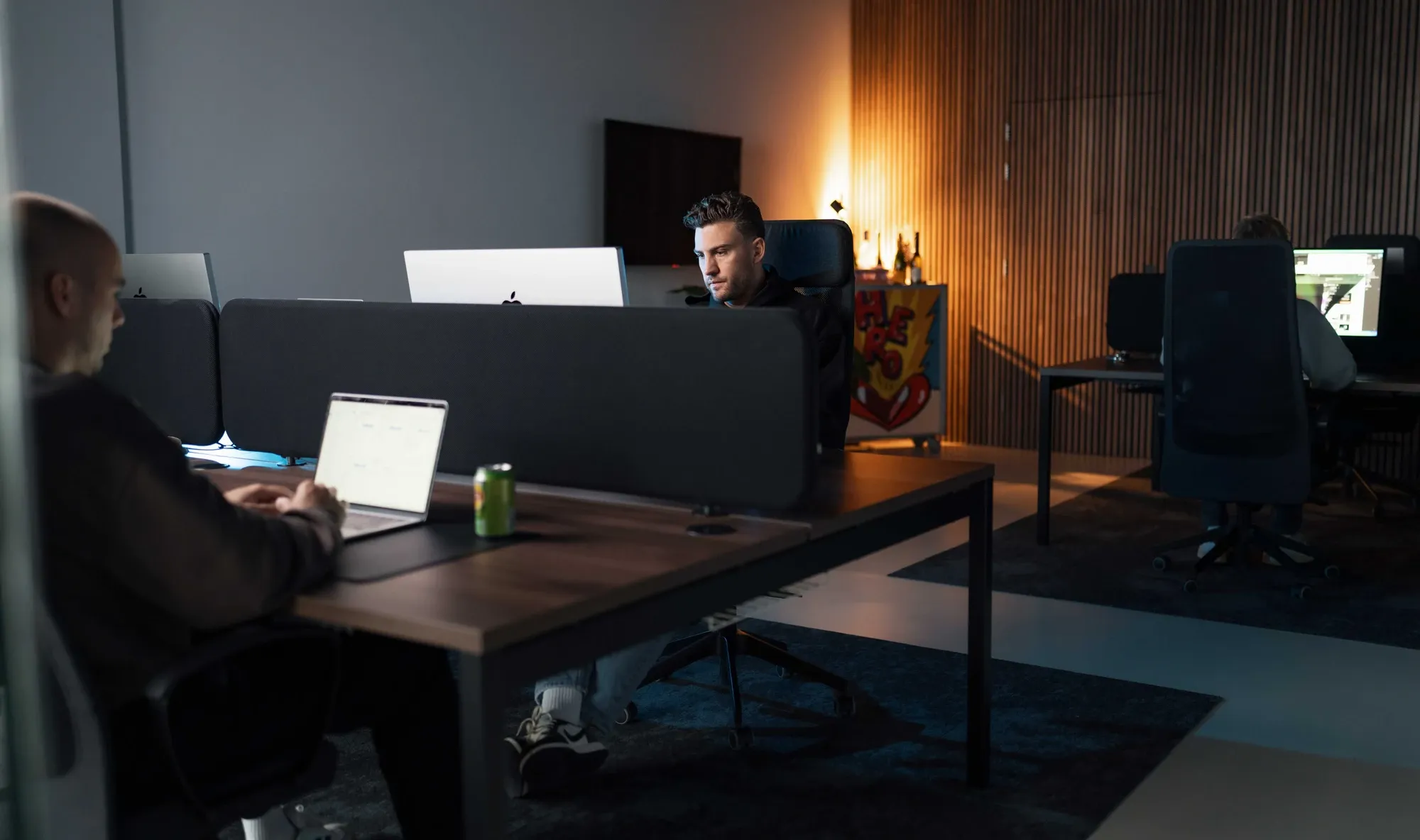 Twee collega’s van Klubb tegenover elkaar aan een dubbel bureau, met de houten wand op de achtergrond