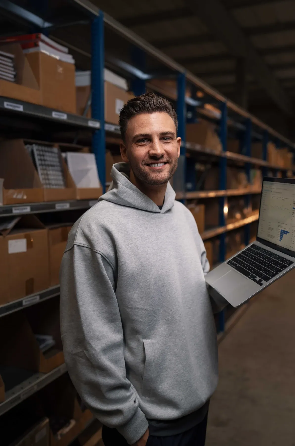 Specialist van Klubb met een laptop met een dashboard, tussen de stellingen van een magazijn